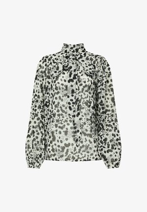 Blusa de manga larga en tejido ligero con un alto cuello y un detalle de lazo, con un patrón de puntos en blanco y negro y puños acanalados.