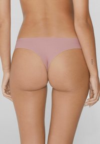 Różowy, gładki string z minimalnym zakryciem, charakteryzujący się niskim stanem pasa i brakiem widocznych szwów.