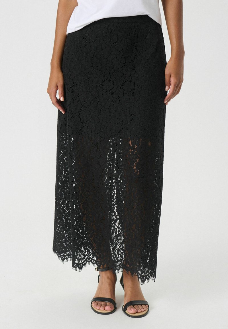Schwarzer Spitzen-Maxi-Rock mit einem gestuften Design und gewelltem Saum. Verfügt über einen taillierten Bund und ein filigranes Blumenmuster. Kombiniert mit schwarzen Sandalen.