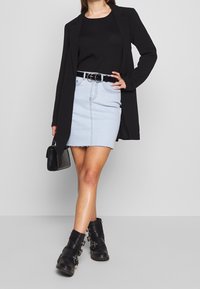 Svart blazer över en svart topp, ljusblå denimkjol med fransad nederkant, svart skärp med silverdetaljer och kraftiga svarta ankelboots.