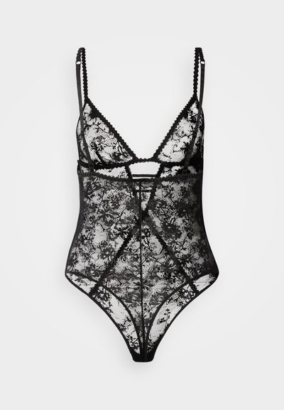 Fekete csipke body áttetsző virágos mintával, állítható vállpántokkal és hullámos szegéllyel. Elöl kivágott részlet jellemzi.