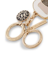 Gold-tone keychain featuring two metal rings, a charm with a black logo, and a tag engraved with "KARL LAGERFELD." Smooth texture.