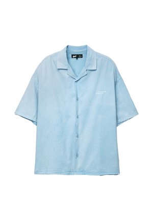Cămașă cu mânecă scurtă și nasturi din material bleu deschis, având un guler cu decupaj și un subtil broderie "Creative Manner" pe partea stângă.