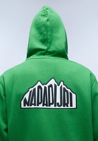Sudadera con capucha verde que presenta un logo de montaña en blanco y negro en la parte posterior. Tejido suave con un corte relajado.