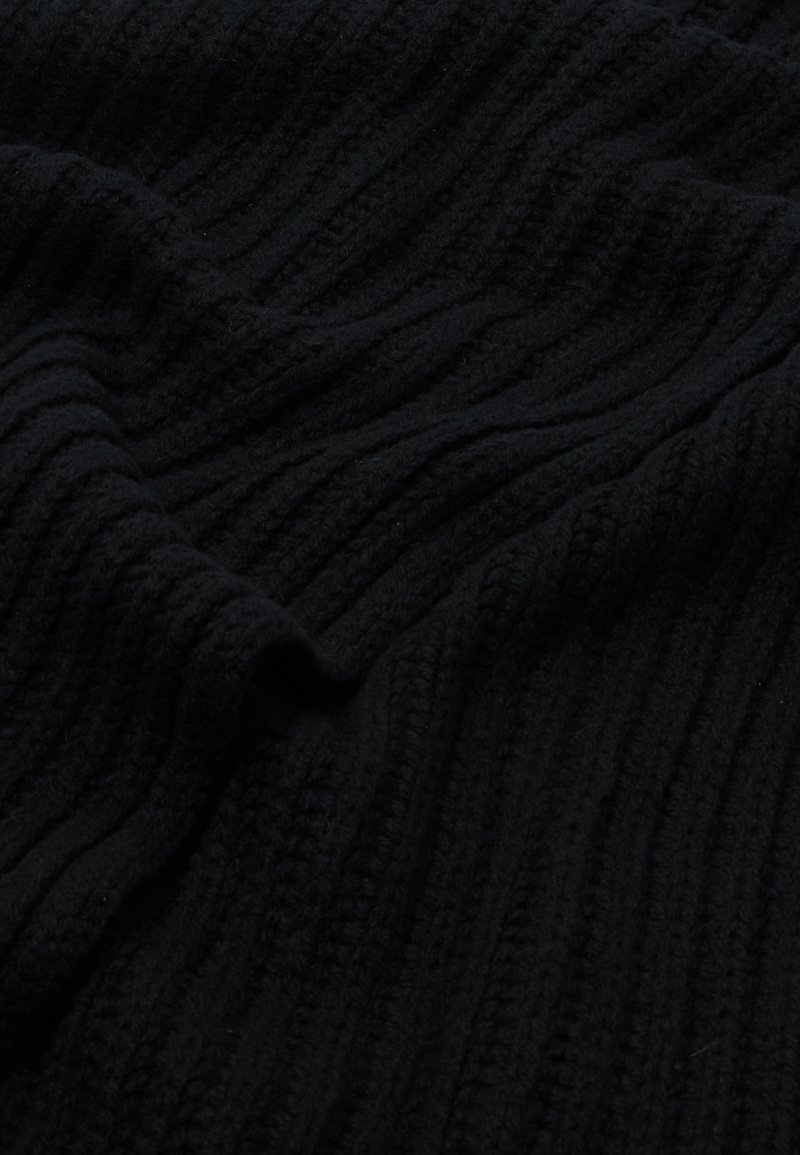 Tissu noir texturé avec un motif en relief, mettant en valeur un matériau doux et tricoté qui se drape doucement en vagues.