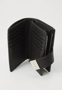 Billetera de piel negra con múltiples compartimentos para tarjetas, un compartimento con cremallera y un cierre magnético. Textura suave con un diseño minimalista.