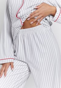 Striped gray pajama set with red accents. The top features a button closure and long sleeves, while the pants have an elastic waistband.