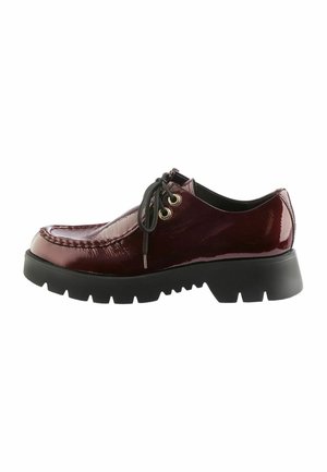 Burgundy patent leather shoe with black chunky sole, lace-up design, gold eyelets, and a moccasin-style toe stitch detail.