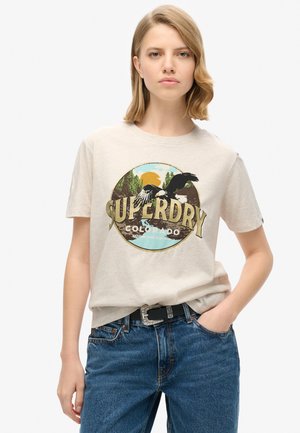 Lys beige bomulds T-shirt med et cirkulært grafisk design, som har teksten "SUPERDRY COLORADO", en ørn og en naturscene i afdæmpede farver.