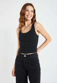 Svart cropped tank topp med rund hals og frontlukking med knapper; laget av glatt stoff med minimal tekstur og en stram passform.