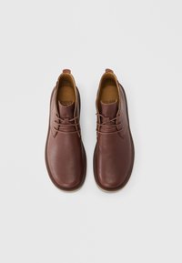 Καφέ δερμάτινα παπούτσια με λείο υλικό, στρογγυλεμένη μύτη και αντίθετο ταμπά εσωτερικό, με κορδόνια και θηλιά για εύκολη φόρεμα.