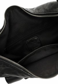 Interno di borsa in pelle nera con fodera in tessuto liscio. Presenta una tasca con cerniera e una zip in metallo argento con dettaglio in pelle testurizzata.