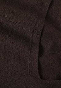 Primo piano di un tessuto lavorato a maglia marrone scuro che mostra la texture e un dettaglio di cucitura o piega.