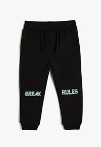Mustat verkkarit, joissa on nauhakuja vyötäröllä. Lahkeissa on vaaleansiniset tekstit "BREAK" ja "RULES". Valmistettu pehmeästä, teksturoidusta kankaasta.