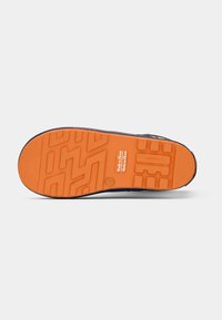Suela de un zapato con suela de goma naranja, patrones texturizados y la etiqueta "Hecho en China" grabada en el centro.