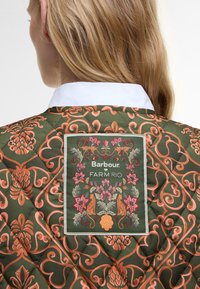 Quilted jacket in dark green with ornate orange floral patterns. Features a fabric label with "Barbour" and "FARM RIO" on the back.
