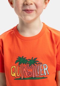 Oranžové bavlněné tričko s barevným logem "Quiksilver" s palmami a designem vlny, kulatým výstřihem a krátkými rukávy.