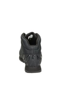 Zapato de senderismo negro con parte superior texturizada y collar acolchado. Presenta una suela robusta y con patrón, además de acentos reflectantes en el talón.