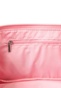 Roze stoffen tas interieur met een gladde textuur, voorzien van een ritsvak en een lichter roze voering. De ritsen trekker is van zilverkleurig metaal.