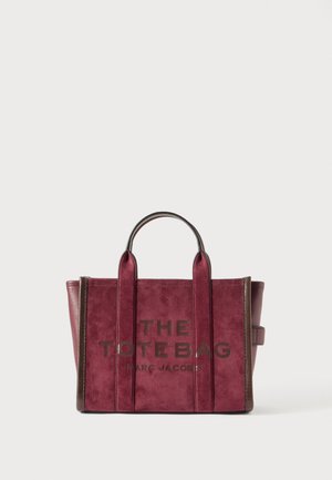 Deep burgundy suede tote bag with brown leather trim, double top handles, and text "THE TOTE BAG MARC JACOBS" on front.