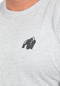 Grijze katoenen t-shirt met een zwarte silhouet van een gorilla op de linkerkant van de borst. De stof heeft een gladde textuur en een casual pasvorm.