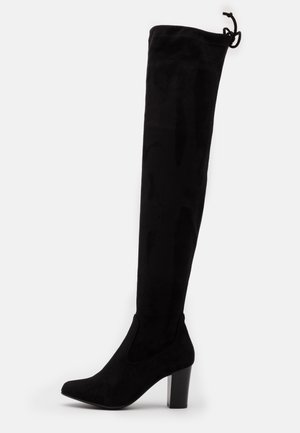 Botte femme en daim noir au-dessus du genou avec bout pointu, talon haut épais et lien ajustable à l'arrière en haut.