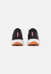 Zapatillas deportivas negras con acentos en rosa, presentando un upper texturizado, una entresuela blanca y una suela naranja. El talón tiene un detalle de raya rosa.