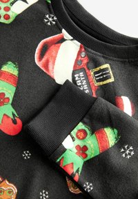 Svart sweatshirt med färgglada julmönster, inklusive tomtar och festliga vantar. Svarta ribbade manschetter och krage. Mjuk textil.