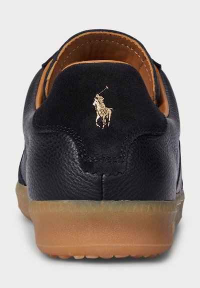 Juodas odinis sportinis batelis su guminėmis padais. Auksu siuvinėtas logotipas ant kulno. Minkšta tekstilinė pamušalas ir tekstūruota viršutinė dalis su subtiliomis siuvimo detalėmis.