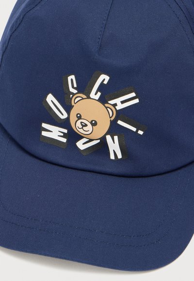Μπλε καπέλο ναυτικού στυλ με γραφικό καρτούν αρκούδας και έντονο κείμενο "HOSCHIN." Κατασκευασμένο από ύφασμα με κυρτό γείσο και ραμμένες λεπτομέρειες.