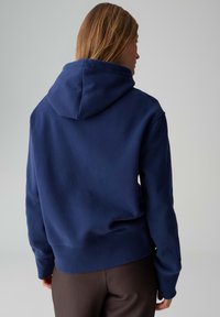 Marineblaue Kapuzen-Sweatshirt aus weichem Stoff. Verfügt über einen gerippten Saum und Bündchen, mit einfachem Design und ohne sichtbare Logos.