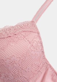 Bralette de encaje rosa con patrones florales, malla texturizada y borde ondulado. Tirantes ajustables con forro suave para mayor comodidad.