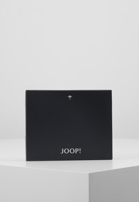 Zwarte rechthoekige doos met een matte textuur. Heeft een zilveren logo en decoratieve details op de bovenkant. Eenvoudig ontwerp met strakke lijnen.