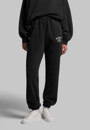 Schwarze Sweatpants aus weichem Stoff, mit elastischem Bund und Bündchen ausgestattet, sowie weißen "Westbury Studio" Logo-Details auf der Rückseite.