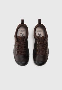 Brązowe skórzane sneakersy z czarnymi gumowymi podeszwami, z misternym sznurowaniem, małym uchwytem na pięcie i wyściełanym kołnierzem dla komfortu.