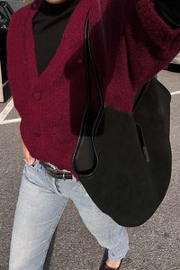 Bordo adīts kardigāns ar divām pogām, kombinēts ar melnu ādas plecu somu un gaiši zilu džinsu. Asfalta fons.