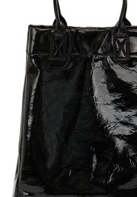 Fekete lakkbőrből készült tote táska fényes felülettel, két strapabíró füllel, téglalap alakú, sima, enyhén gyűrött textúrával.