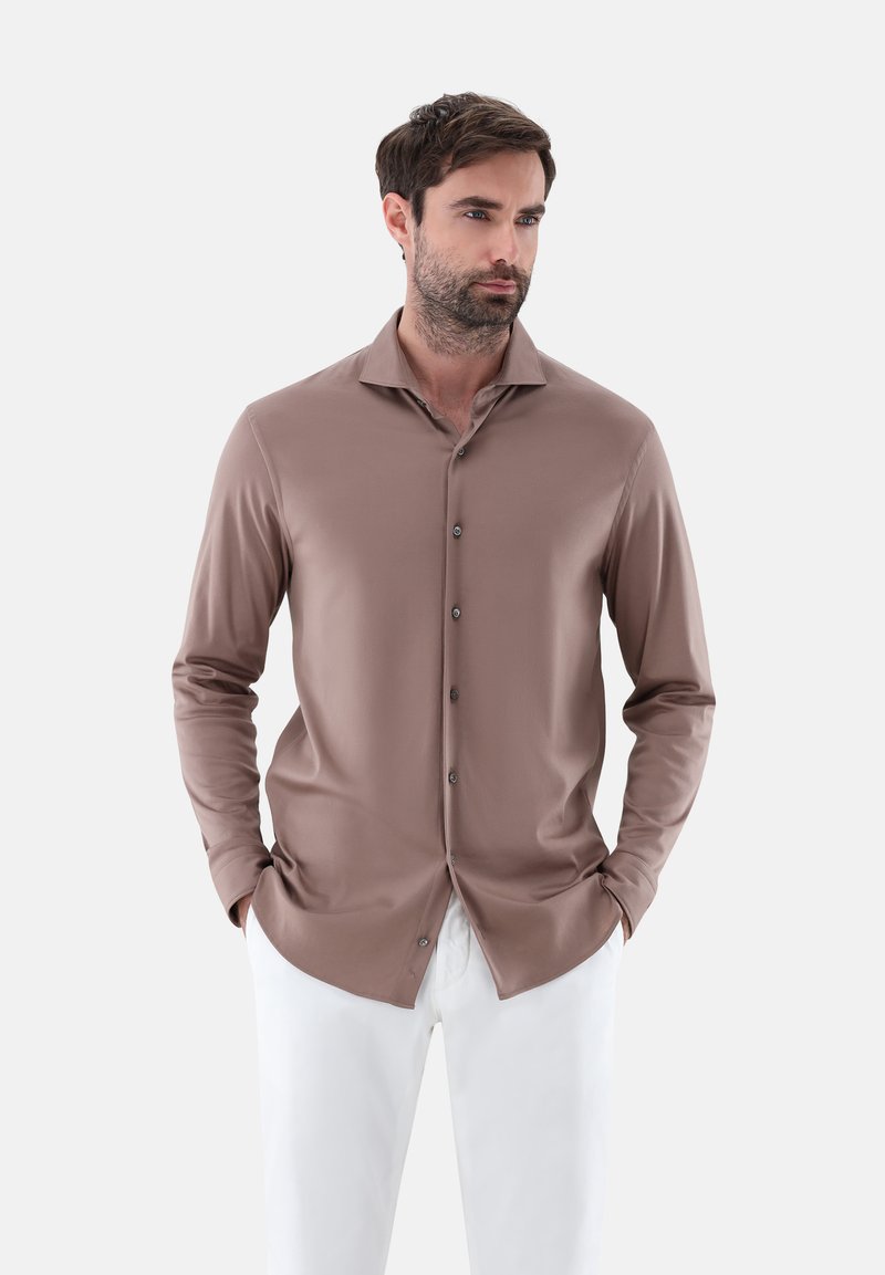 Langärmliges Button-Down-Hemd aus einem muted braunen Stoff, mit einem Umlegkragen, glatter Textur und dunklen Knöpfen, kombiniert mit weißen Hosen.