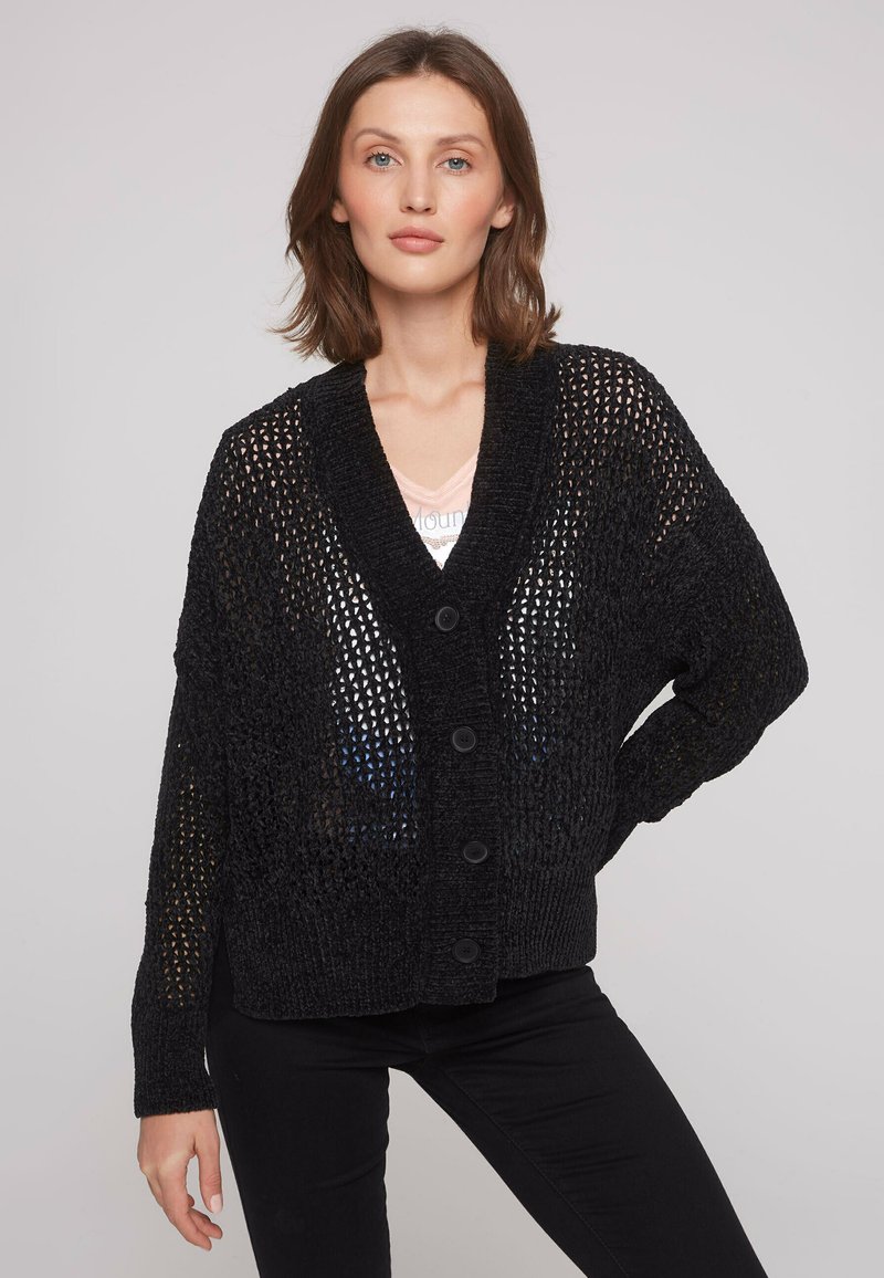 Cardigan noir en maille ouverte avec un col en V, des manches longues et cinq boutons à l'avant. Présente une coupe ample et un tissu texturé.