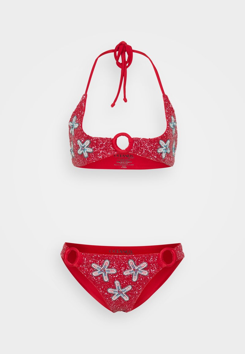 Conjunto de biquíni vermelho com um top halter com desenhos de estrelas-do-mar e detalhes brilhantes, e parte de baixo correspondente com anéis nos lados.