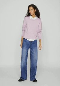 Light purple knitted sweater, crew neck, paired with wide-leg blue denim jeans. The outfit features a white collared shirt underneath.