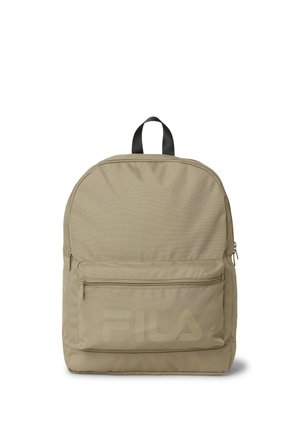 Mochila beige con bolsillo frontal con cremallera, asa negra y logo discreto de FILA en el bolsillo, mostrada sobre un fondo blanco.