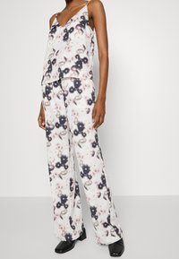 Ensemble deux pièces à motifs floraux dans des couleurs claires ; haut sans manches avec décolleté en V et pantalon léger ; fabriqué à partir d'un tissu doux et léger.