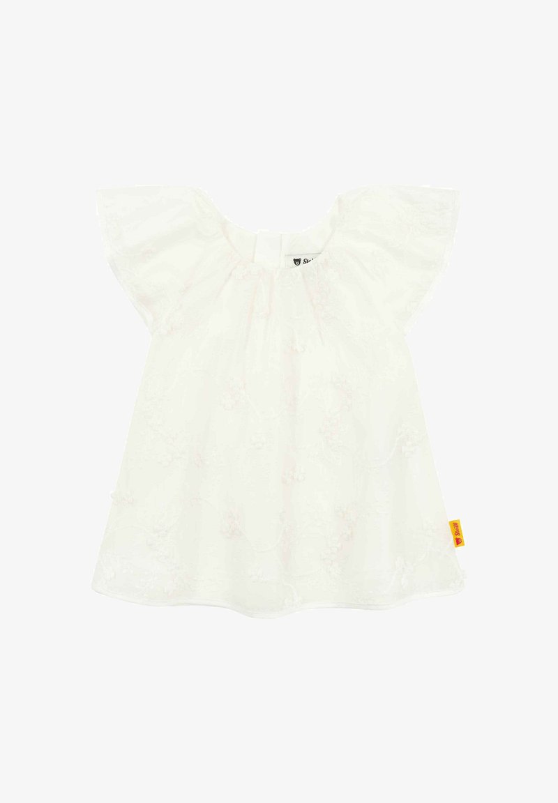 Weißes Kurzarmoberteil mit strukturiertem Blumenmuster, gerafftem Ausschnitt und einem kleinen Etikett in der unteren rechten Ecke. Weicher, leichter Stoff.