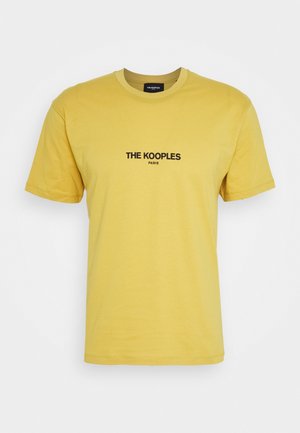 Keltainen puuvillainen t-paita, jossa on pyöreä kaula-aukko, lyhyet hihat ja edessä musta logoprintti, jossa lukee "THE KOOPLES PARIS".
