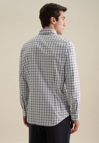 Camicia a maniche lunghe a quadri blu e bianchi con colletto a punta. Presenta un orlo curvo e dettagli con polsini abbottonati. Tessuto in cotone.