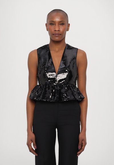 Blouse noire à paillettes avec un décolleté en V profond et un ourlet peplum évasé. Texture lisse, design sans manches. Le modèle porte un pantalon sombre.