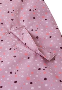 Rosa Stoff mit einem verstreuten Blumenmuster in Weiß, Rosa und Dunkellila. Enthält ein Detail mit einem Klettverschluss aus Stoff.