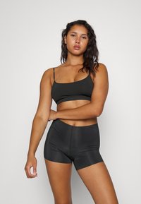 Svart tettsittende sportsbh med tynne stropper og høy midje shorts i et glatt, elastisk materiale, med sømløst design for komfort.