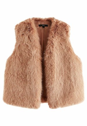Femme marchant sur le trottoir portant une chemise blanche oversize, un gilet en fausse fourrure beige, un pantalon en cuir noir et des bottes noires à talons montant jusqu'aux genoux.